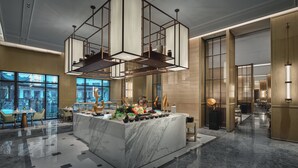 Eine moderne Hotelhalle mit einem мрамор Reception Desk, einer geometrischen Hängeleuchte und großen Fenstern mit Blick auf die Stadt.