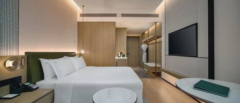 Una habitación de hotel moderna con cama, mesita de noche, televisor y una pequeña mesa redonda.