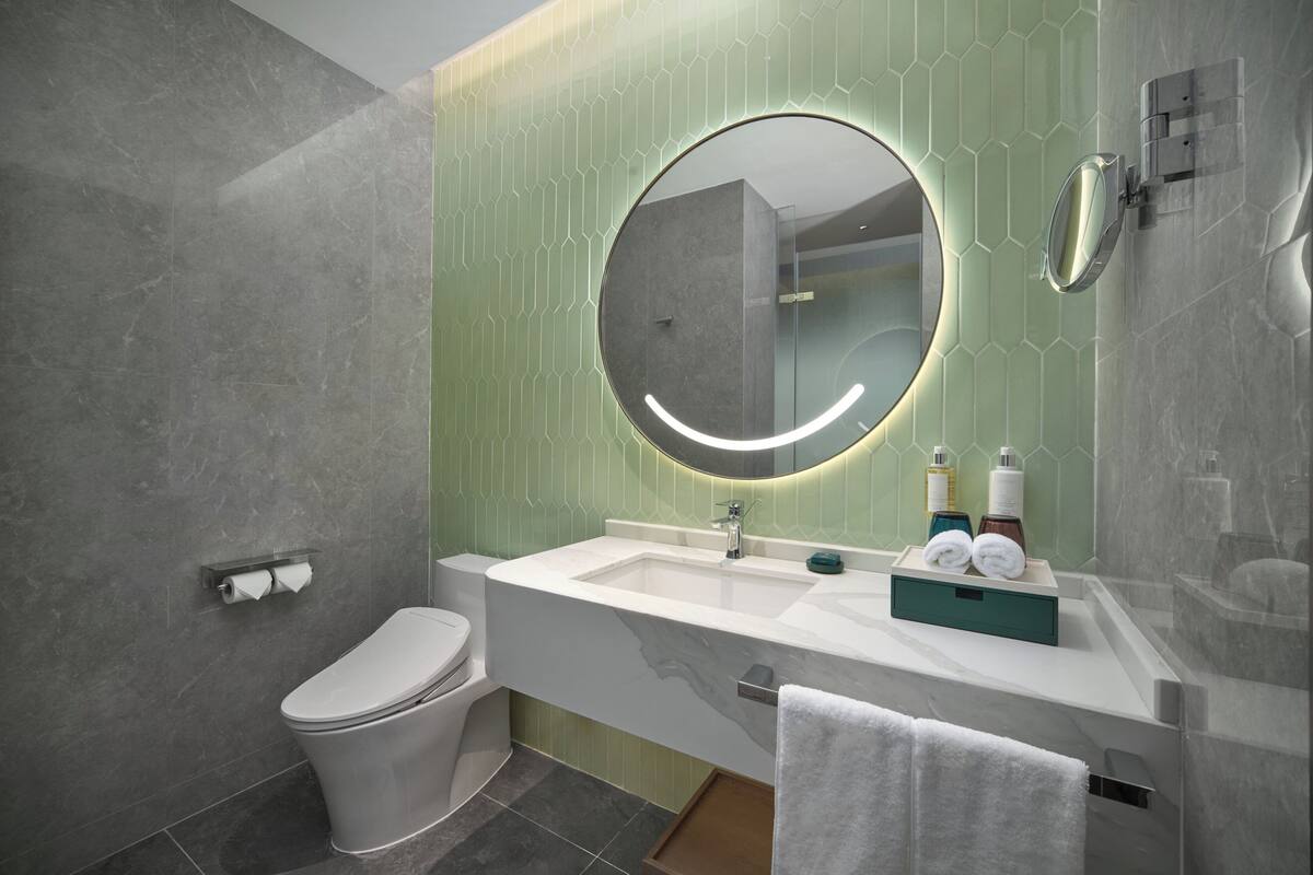 Un baño moderno con inodoro, lavamanos y espejo.