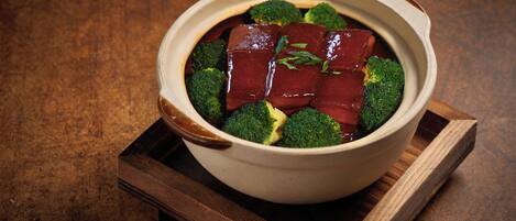 A bowl of food with meat and broccoli on a wooden tray.