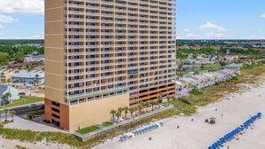 A high-rise hotel with multiple balconies, a beachside location, and a parking area. - Luxury 23rd floor  Penthouse End Unit-Panoramic Ocean Front Views-Beach Service (Panama City Beach)