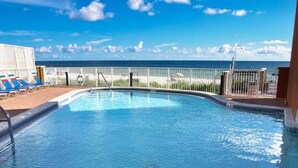 A swimming pool with a view of the ocean, a fenced area with lounge chairs, and a clear sky. - Luxury 23rd floor  Penthouse End Unit-Panoramic Ocean Front Views-Beach Service (Panama City Beach)