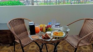 A breakfast table with wicker chairs on a balcony, featuring a variety of food and drinks. - Pousada Maceió é Massa Frente ao Mar (Maceió)
