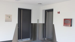 Un ascensor amb un panell de control, un detector d'incendis i el número de porta 14.