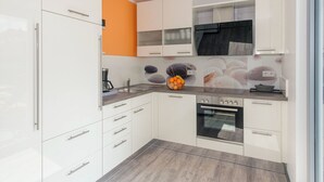 Eine moderne Küche mit weißen Schränken, einem eingebauten Backofen und einer Kaffeemaschine.