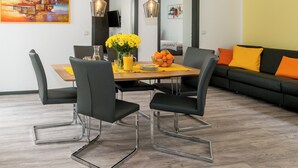 Ein moderner Essbereich mit einem Holztisch, schwarzen Stühlen und einer Vase mit gelben Blumen.