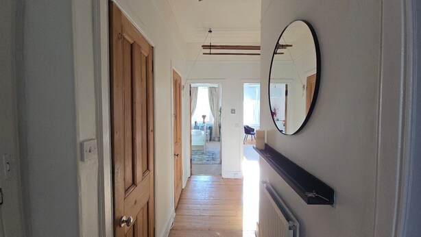 A hallway with wooden doors, a mirror, and a radiator.