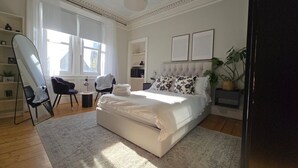 A modern bedroom with a large bed, a desk, and a chair.