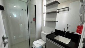 A modern bathroom with a glass-enclosed shower, a white toilet, and a black sink with a mirror above it. - RN STUDIO - APTO 1008 (Maceio)