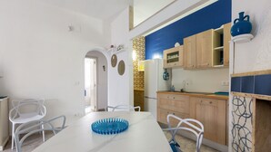 Eine moderne Küche mit weißen Schränken, einer blauen Spritzschutzwand und einem weißen Esstisch mit Stühlen.