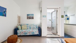 Ein Wohnzimmer mit einer Couch, einem Hocker und einem Esstisch.