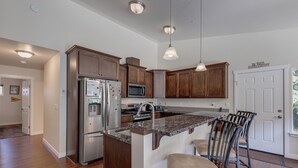 A modern kitchen with dark wood cabinets, stainless steel appliances, and a granite island with bar stools. - A Re-styled Single Story, 3-bedroom, 2-bath Ranch Style Cabin at Silver Lake (Maple Falls)