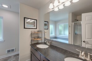 A bathroom with two sinks, a large mirror, and a shower. There are framed pictures on the wall and a window providing natural light. - A Re-styled Single Story, 3-bedroom, 2-bath Ranch Style Cabin at Silver Lake (Maple Falls)