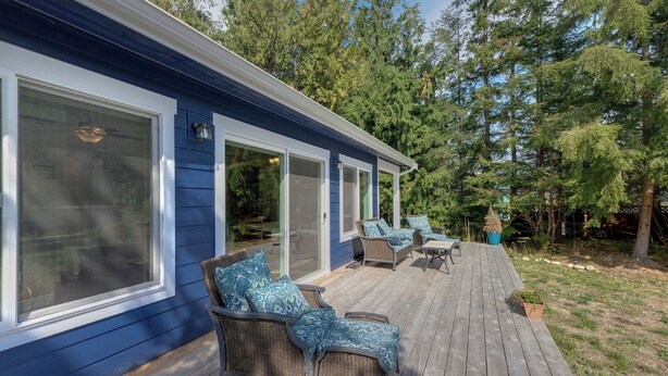 A covered deck with wicker furniture and a potted plant. - A Re-styled Single Story, 3-bedroom, 2-bath Ranch Style Cabin at Silver Lake (Maple Falls)