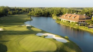 A golf course with a clubhouse and a body of water.