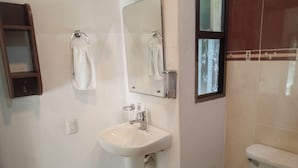 A bathroom with a white sink, a mirror, and a toilet. There is a towel rack above the sink and a small cabinet to the left. - Wonderful space with 2 beds, overlooking the pool, downtown Tulum- Huanal H (Tulum)