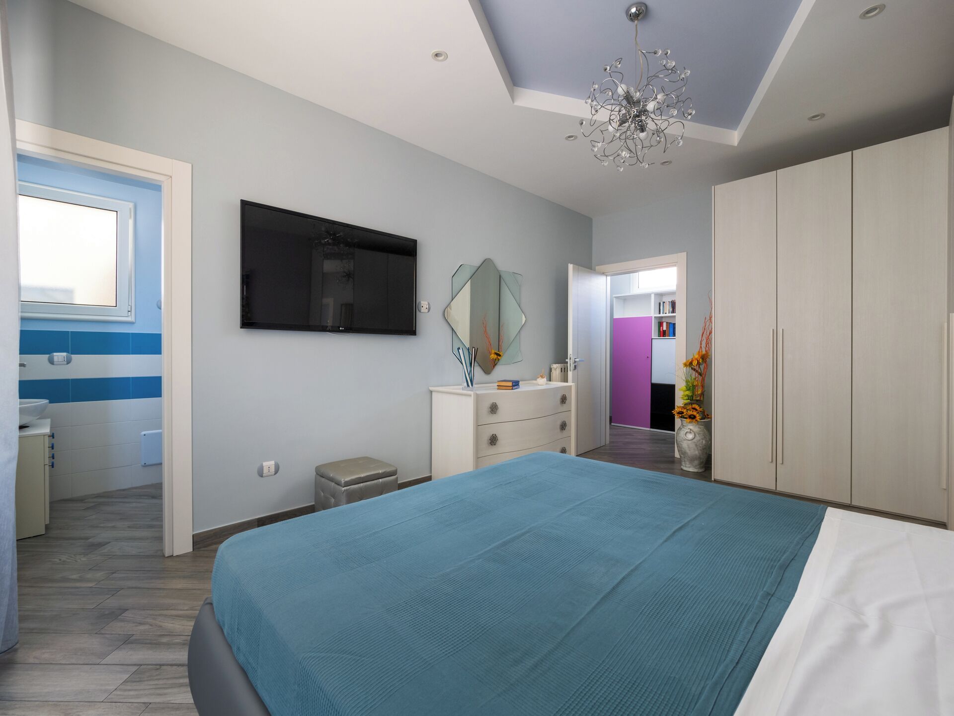 Ein Schlafzimmer mit einem Bett, einem Fernseher, einer Kommode und einem Kleiderschrank.