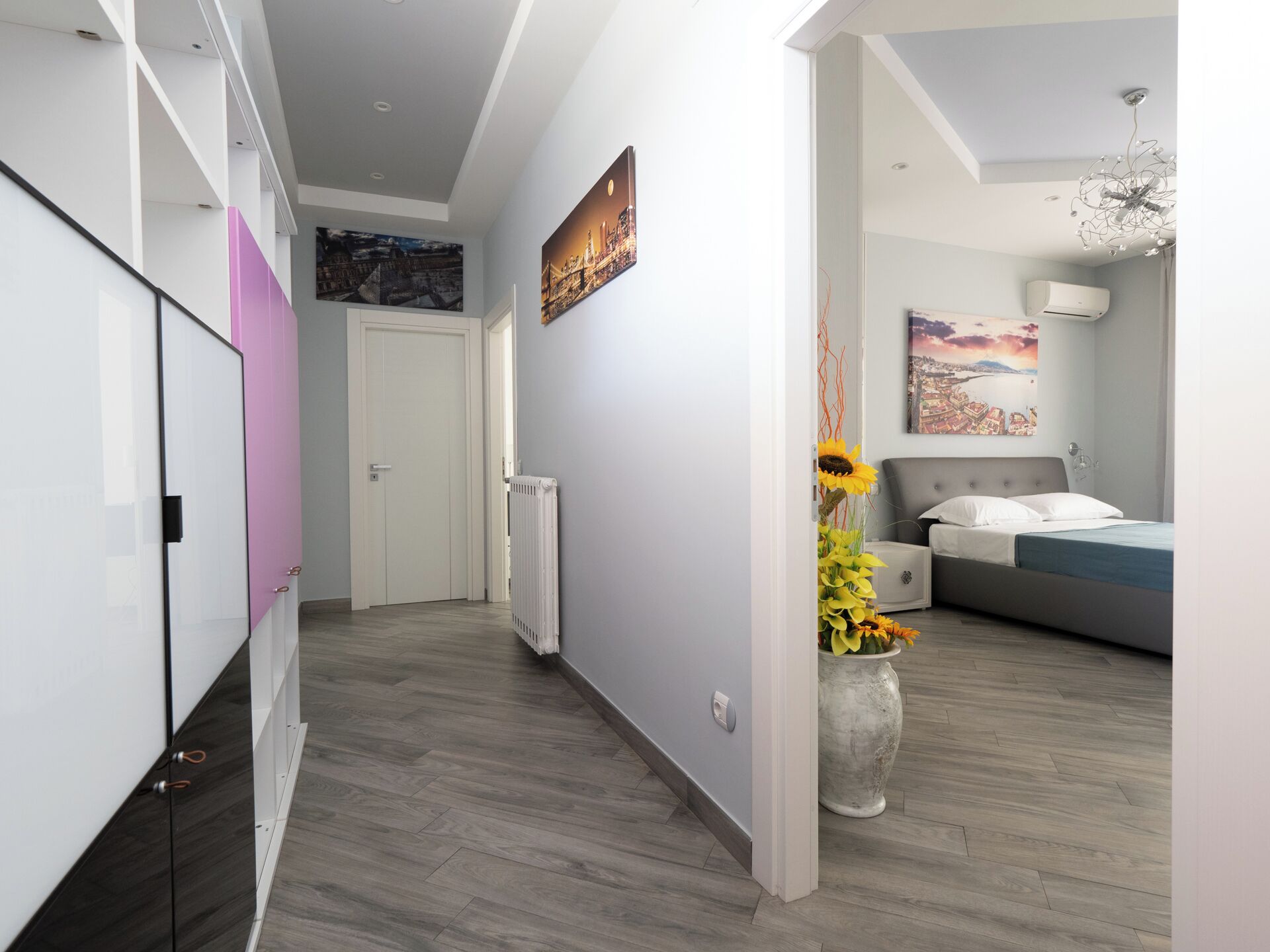 Une chambre moderne avec un lit, une table de chevet, une grande fenêtre et un climatiseur fixé au mur.