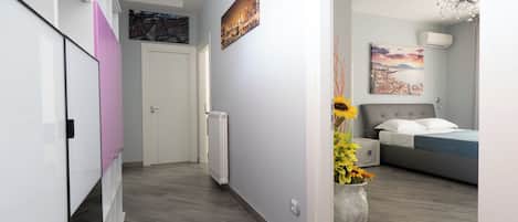 Un dormitorio moderno con una cama, una mesita de noche, un ventanal grande y un aire acondicionado instalado en la pared.