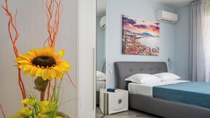 Une chambre à coucher moderne avec un lit, une table de chevet, un miroir et un tableau représentant un paysage urbain.