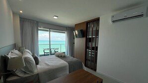 A hotel room with two beds, a desk, a TV, and a view of the ocean. - RN STUDIO - APTO 1009 (Maceio)