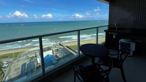 A balcony with a view of the ocean and beach, a small table, and a chair. - RN STUDIO - APTO 1009 (Maceio)