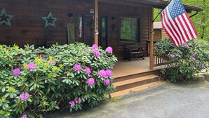 A wooden cabin with a porch, a welcome sign, and an American flag.