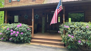 A wooden cabin with a porch, a welcome sign, and an American flag.