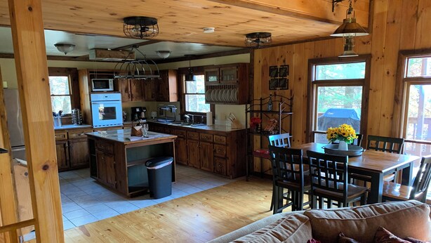 A spacious kitchen with wooden cabinets, a central island, and a dining area with a table and chairs.