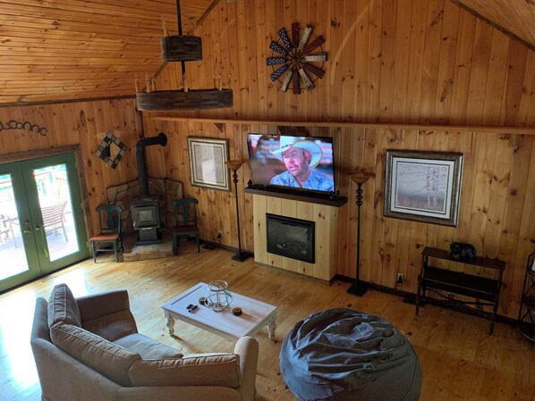 Un intérieur de chalet chaleureux avec une cheminée, un téléviseur et un décor rustique.