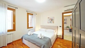 A hotel room with a large bed, a bedside table, a radiator, and a window with curtains. - DolceVita Apartments N. 519 (Venice)