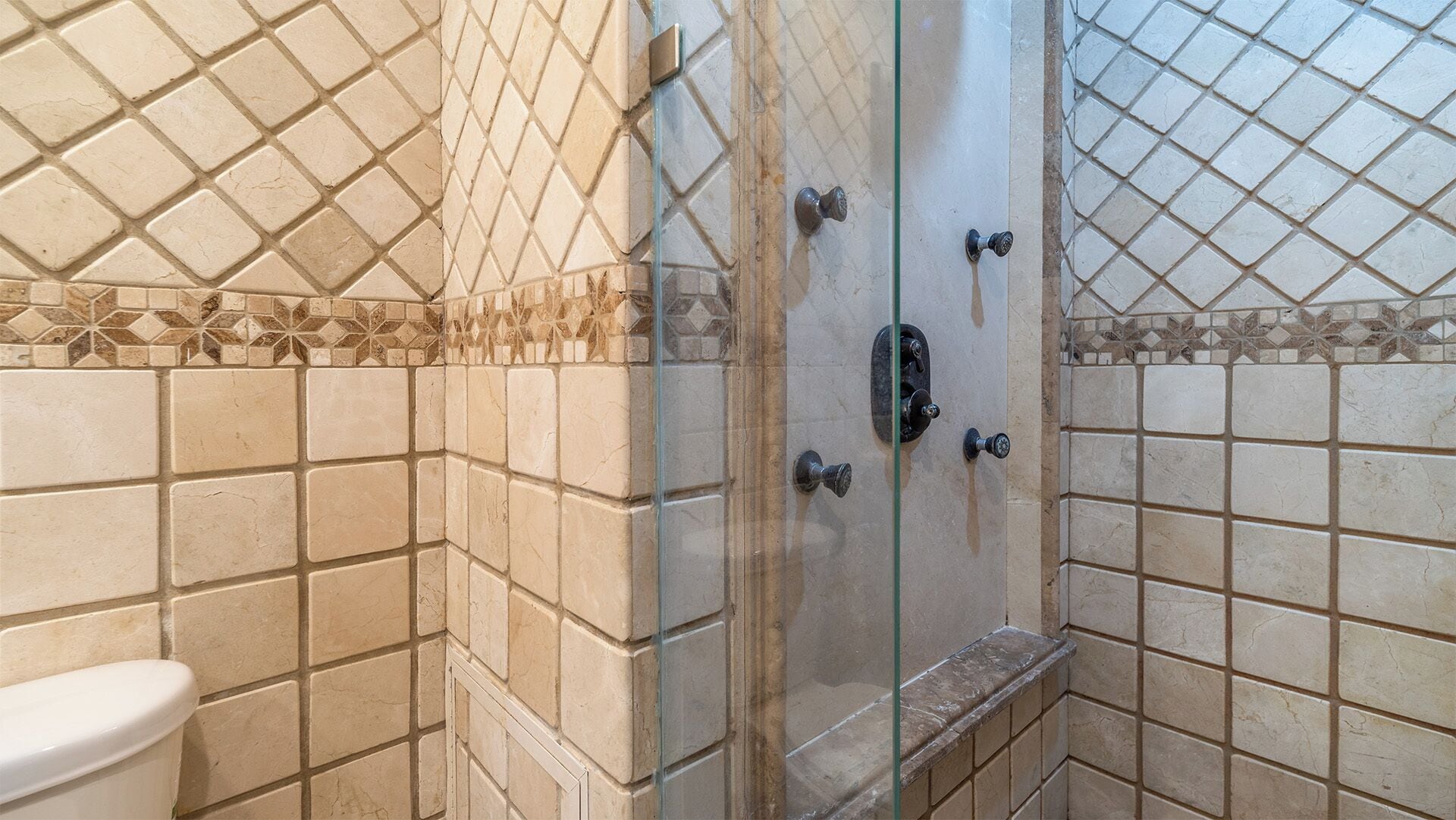 A bathroom with tiled walls, a glass shower enclosure, and a toilet.