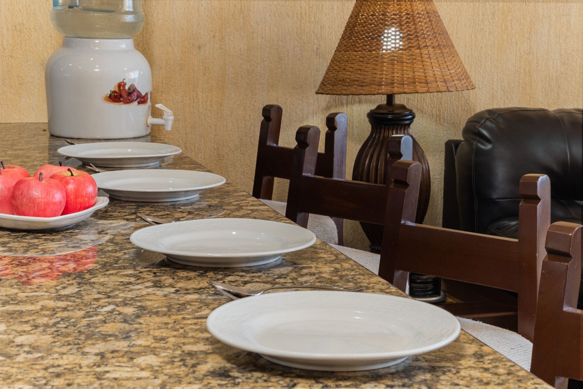 A dining table with plates, a water dispenser, and a lamp.
