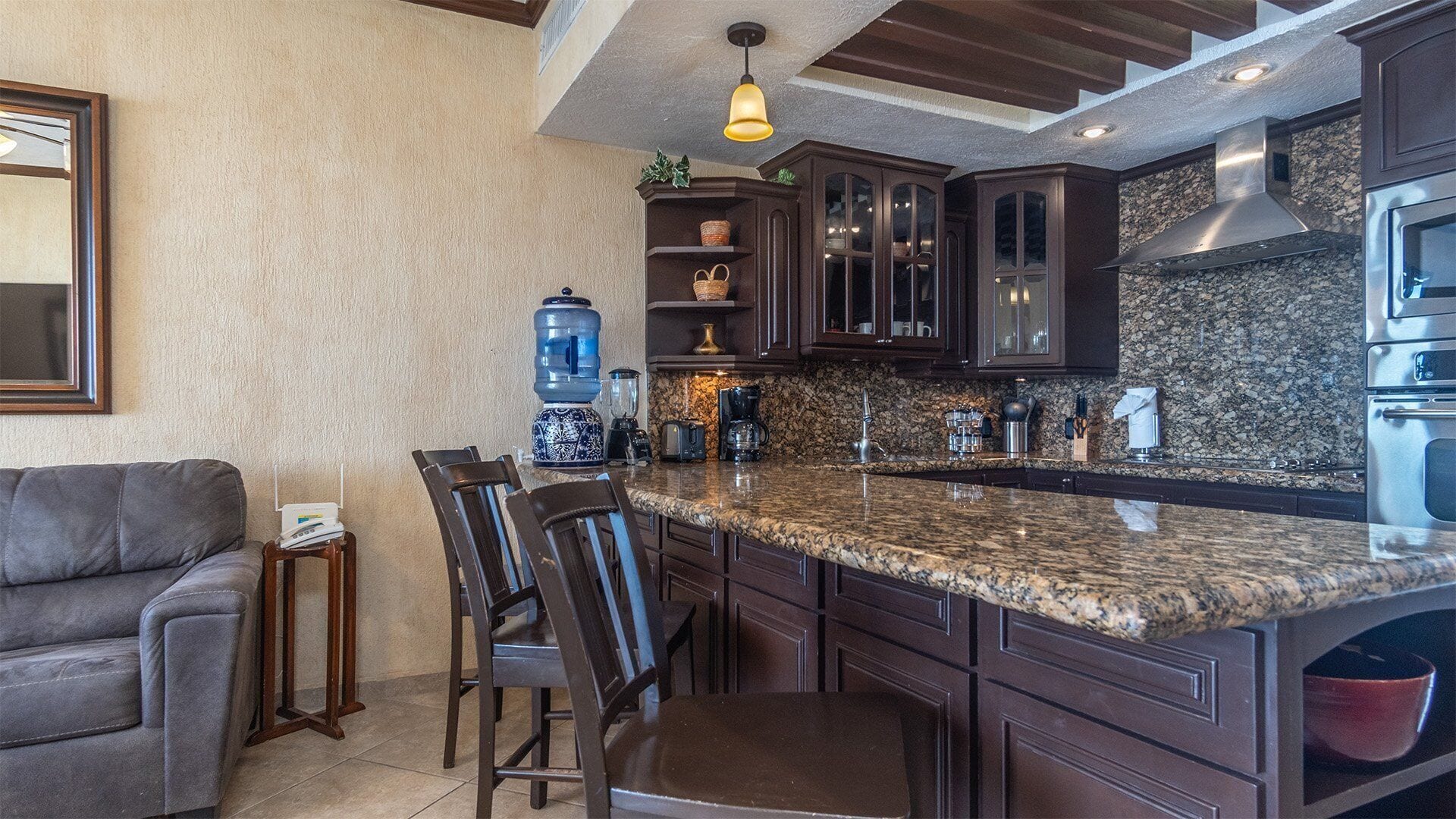 A kitchen with dark wood cabinets, a granite countertop, and a built-in oven.