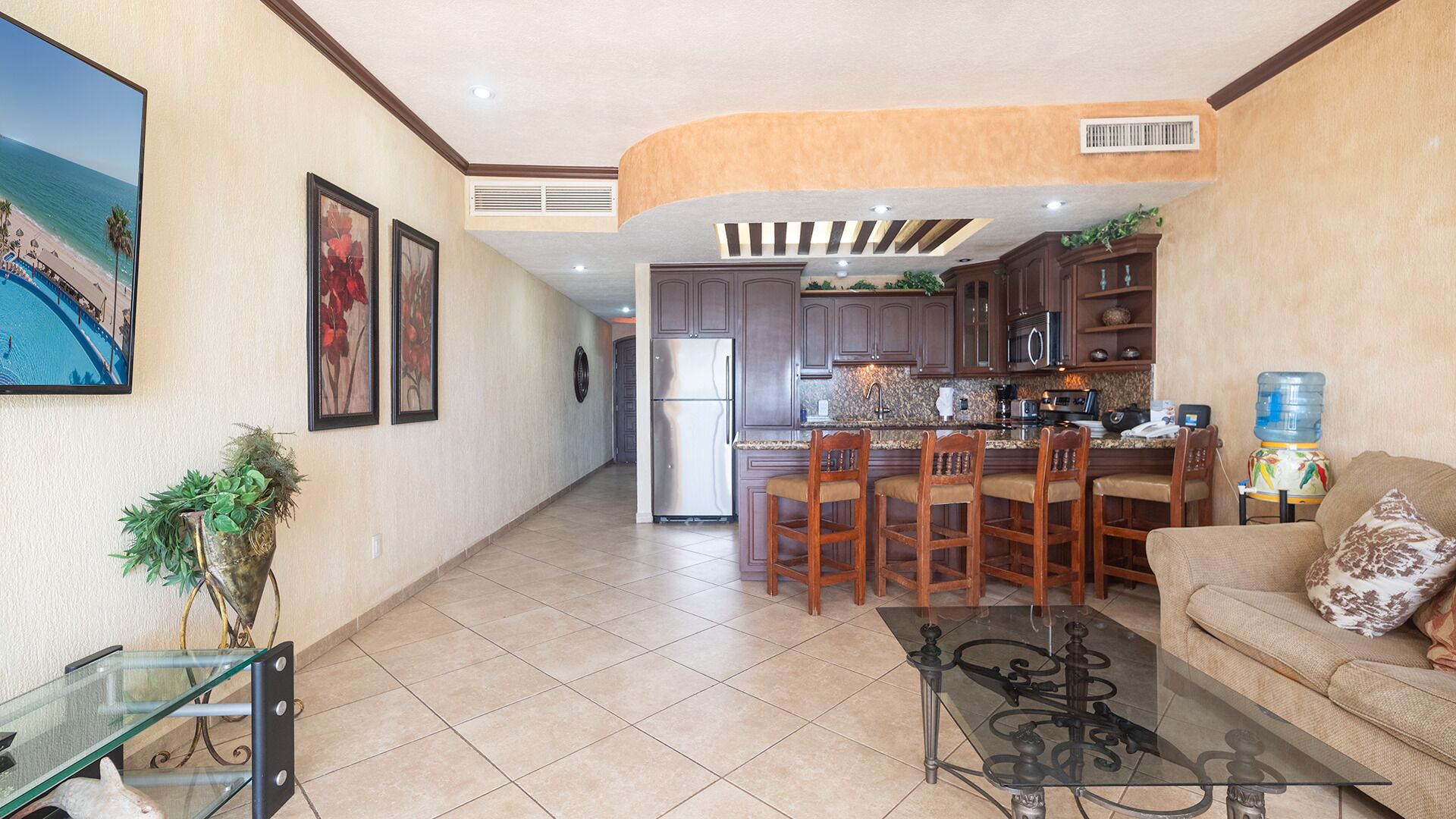 A spacious living area with a kitchen, a dining area with bar stools, and a large window with a view of the beach.