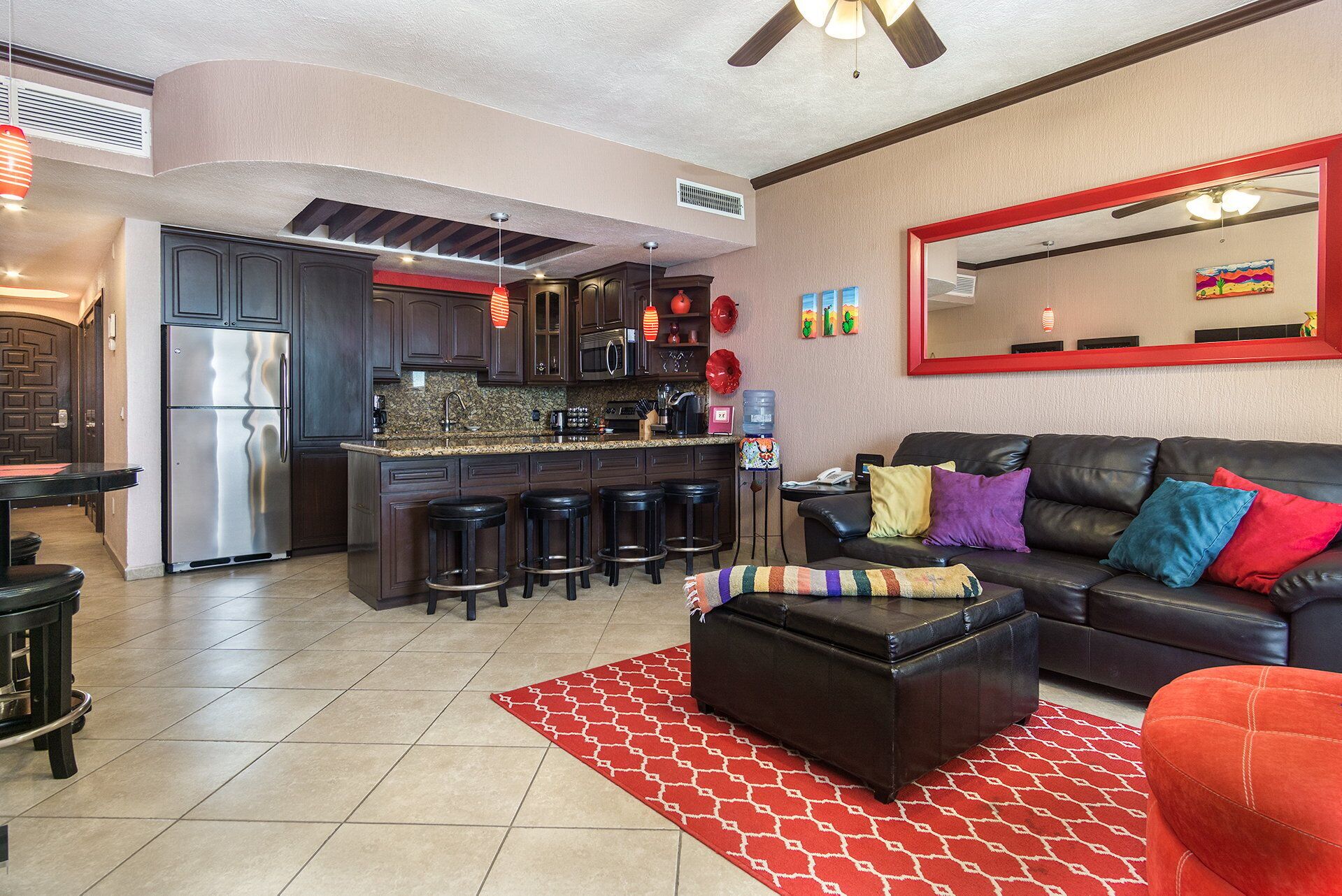 A modern kitchen with dark cabinetry, a stainless steel refrigerator, and a central island with stools.