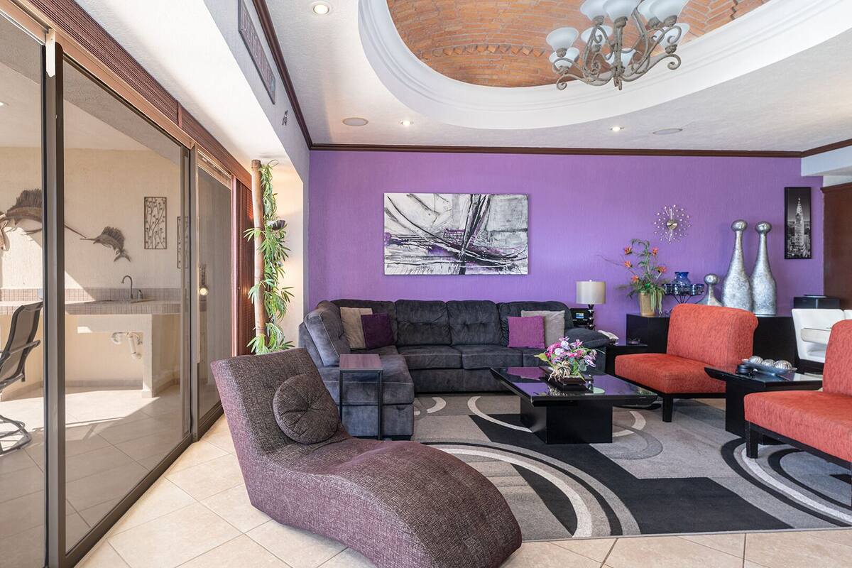 Un salon moderne avec un mur violet, une cheminée, un canapé et une table basse.