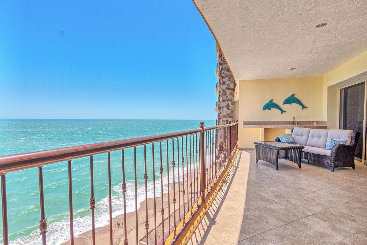 Un balcone con vista sull'oceano, un divano e due decorazioni a tema delfini.