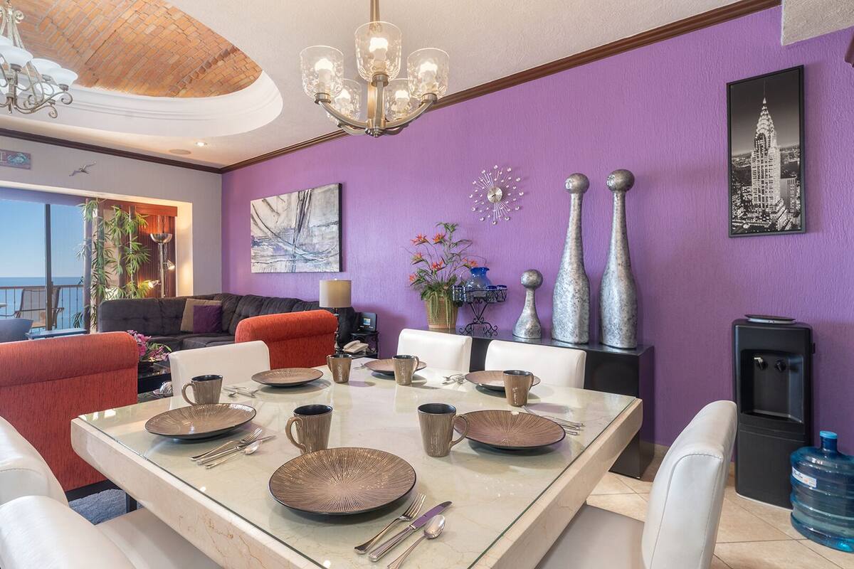 Un coin repas avec une table dressée pour quatre personnes, un canapé et une vue sur la mer.