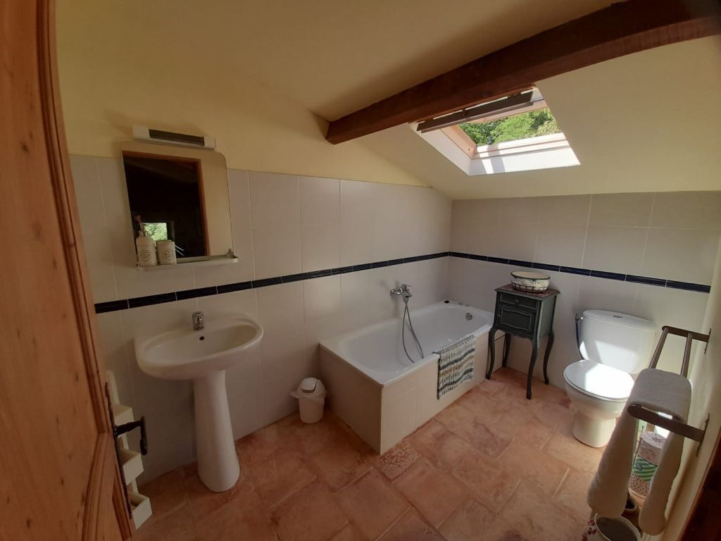 Ein Badezimmer mit Badewanne, Waschbecken und Toilette. Über der Badewanne befindet sich ein Oberlicht.