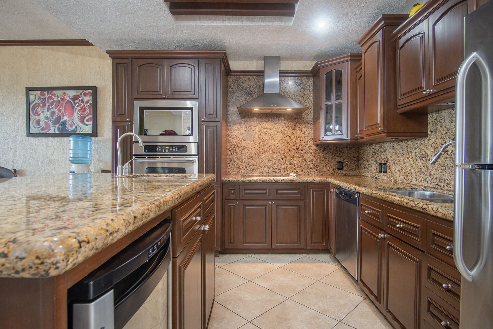 Una cocina con encimeras de granito, electrodomésticos de acero inoxidable y armarios de madera.