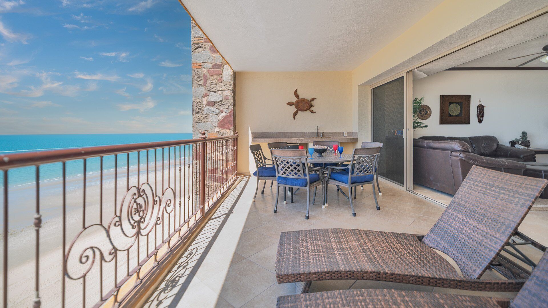 A balcony with a view of the sea, a dining area with chairs and a table, and a sofa.