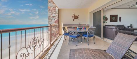 Un balcon avec vue sur la mer, un coin repas avec des chaises et une table, et un canapé.