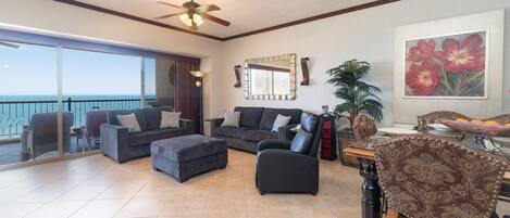 A spacious living room with a balcony overlooking the sea, furnished with sofas and a coffee table.