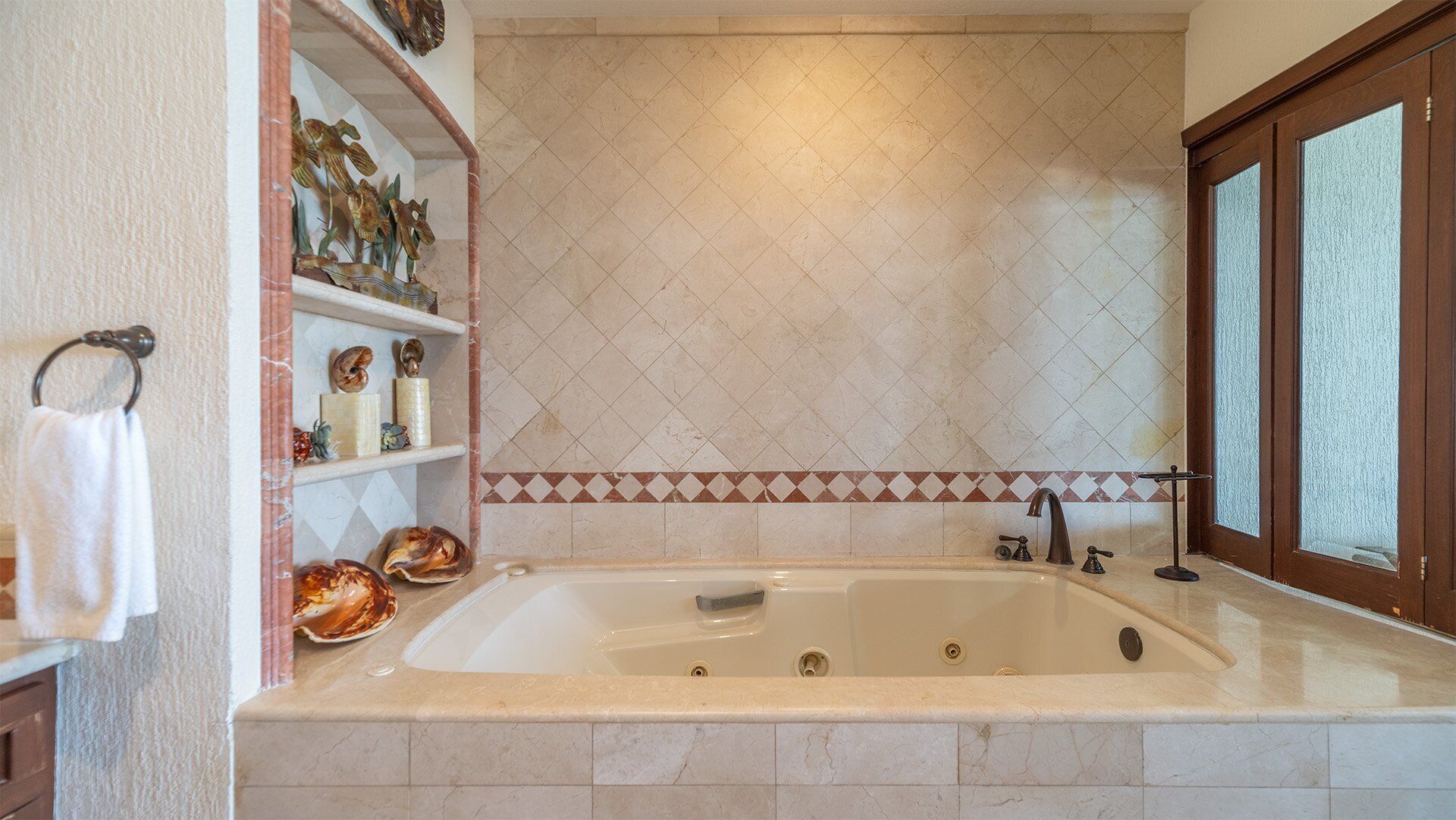 Un bagno con una vasca freestanding, un porta asciugamani e scaffali con oggetti decorativi.