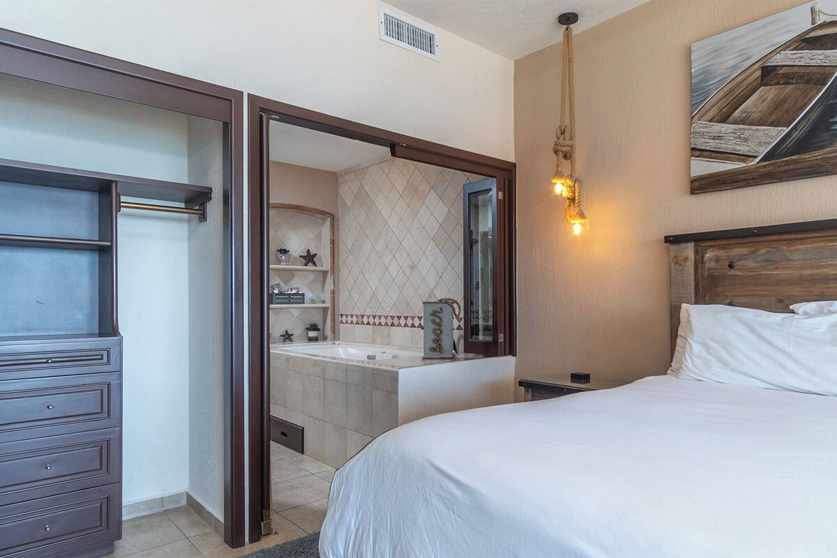 Een hotelkamer met een bed, een kaptafel, een spiegel en een badkamer die door een open deur zichtbaar is.