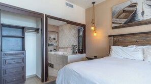 A hotel room with a bed, a dresser, a mirror, and a bathroom visible through an open door. - Sonoran Sky III (Puerto Peñasco)