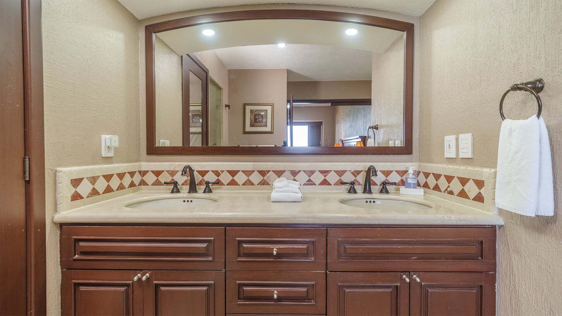 A bathroom with two sinks, a large mirror, and a towel rack.