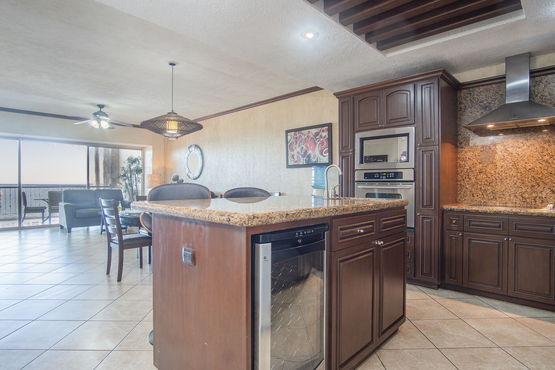 A modern kitchen with granite countertops, stainless steel appliances, and dark wood cabinetry.