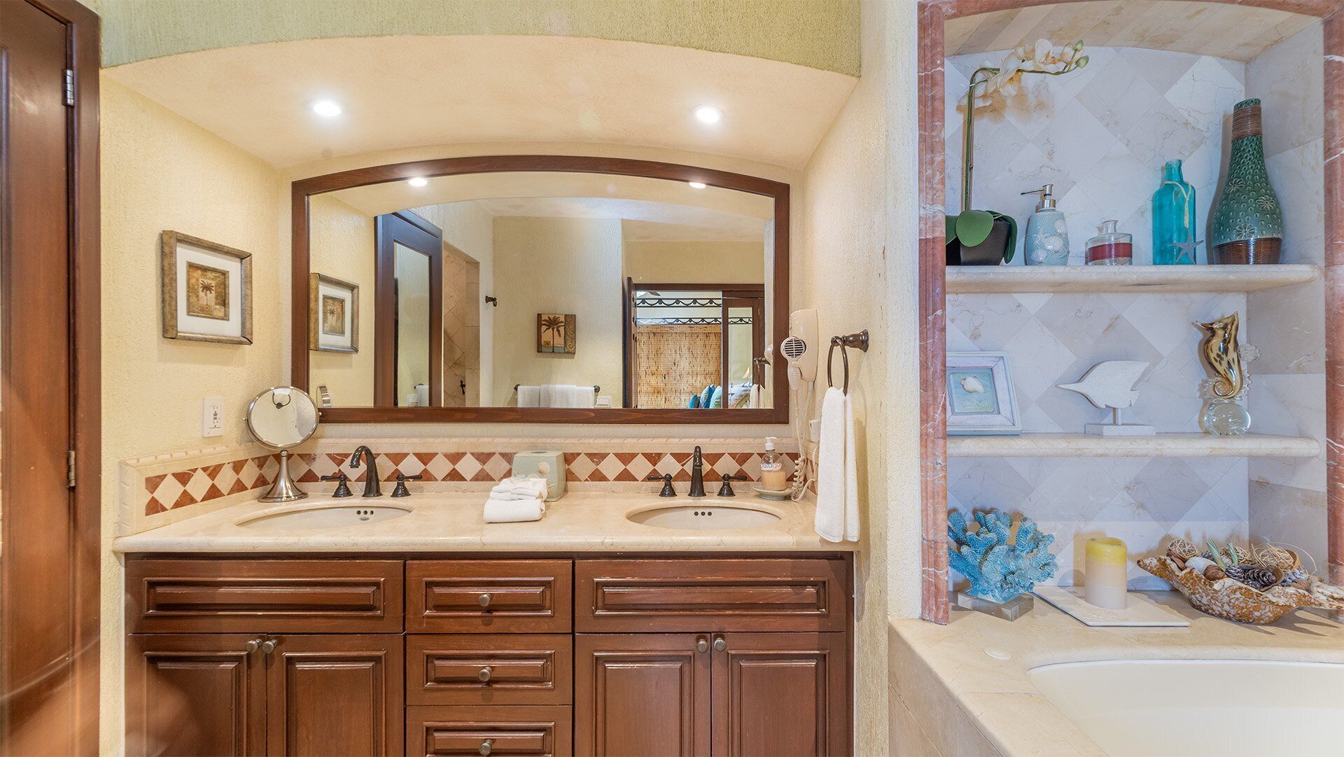 A bathroom with two sinks, a large mirror, and a vanity with multiple drawers.